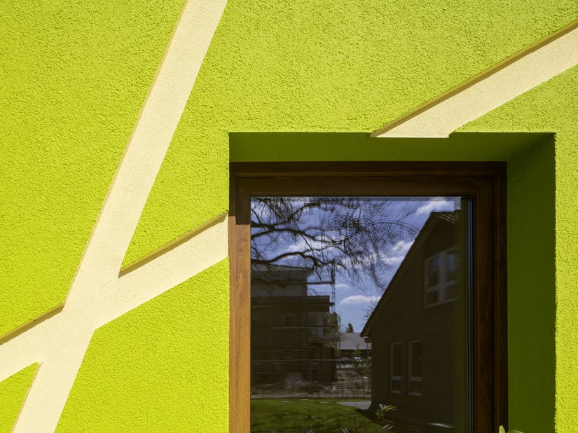 Le finestre, realizzate in legno naturale, compensano l'intensità dei colori.