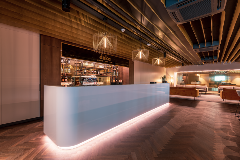 Particolarmente elegante è il design del bar per i visitatori, in cui domina un rivestimento per soffitto satinato realizzato con Sedagloss. Il gioco di rimandi con i dettagli dorati crea un ambiente piacevolmente armonioso.