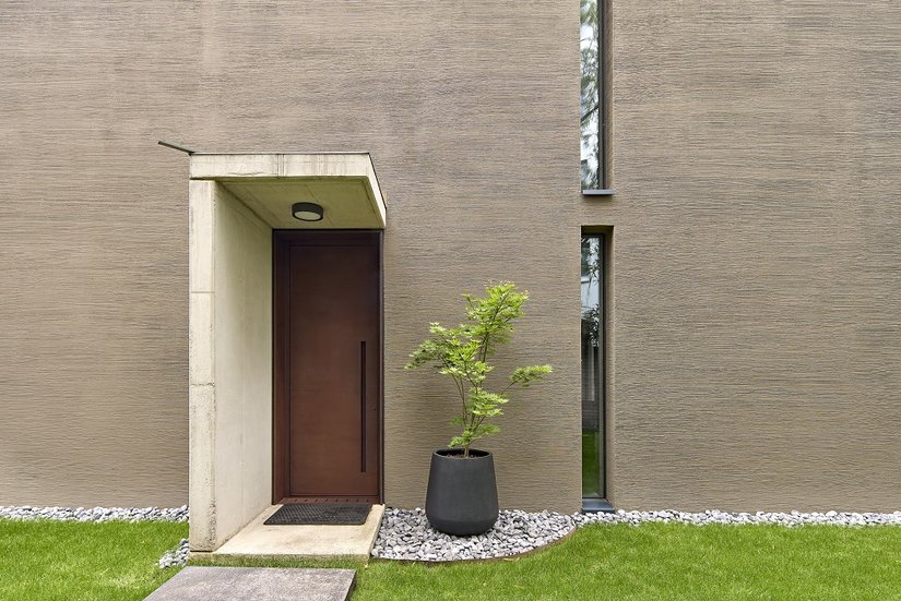 Le finestre in legno scuro sono molto discrete dal punto di vista estetico, mentre la massiccia porta d'ingresso in acciaio Corten è una chiara dichiarazione di stile