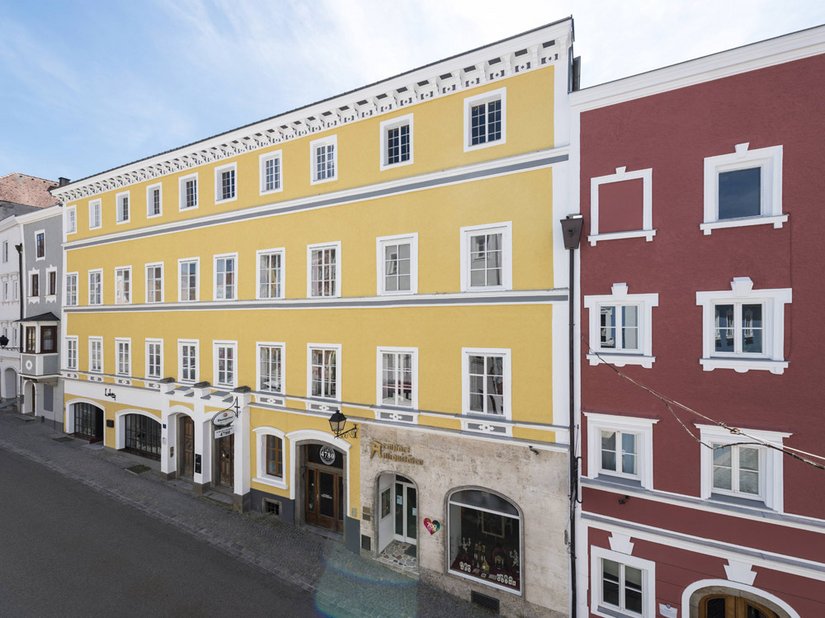 L'abbinamento cromatico giallo ocra - grigio e la casa vicina con il suo spiccato rosso mattone collega le due metà della casa.